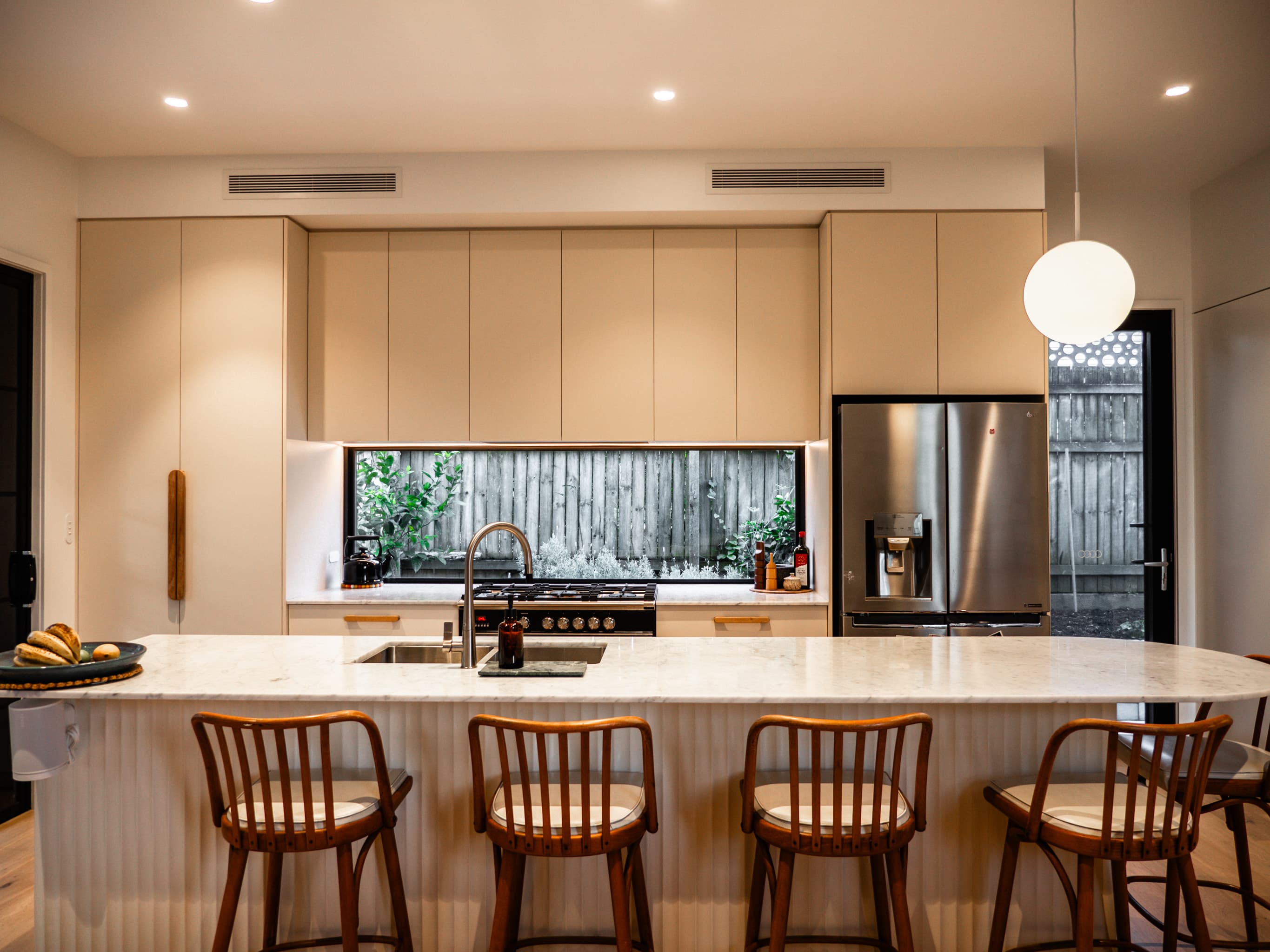 Jacaranda Highside kitchen with a marble island, pale joinery and a window splashback to the garden