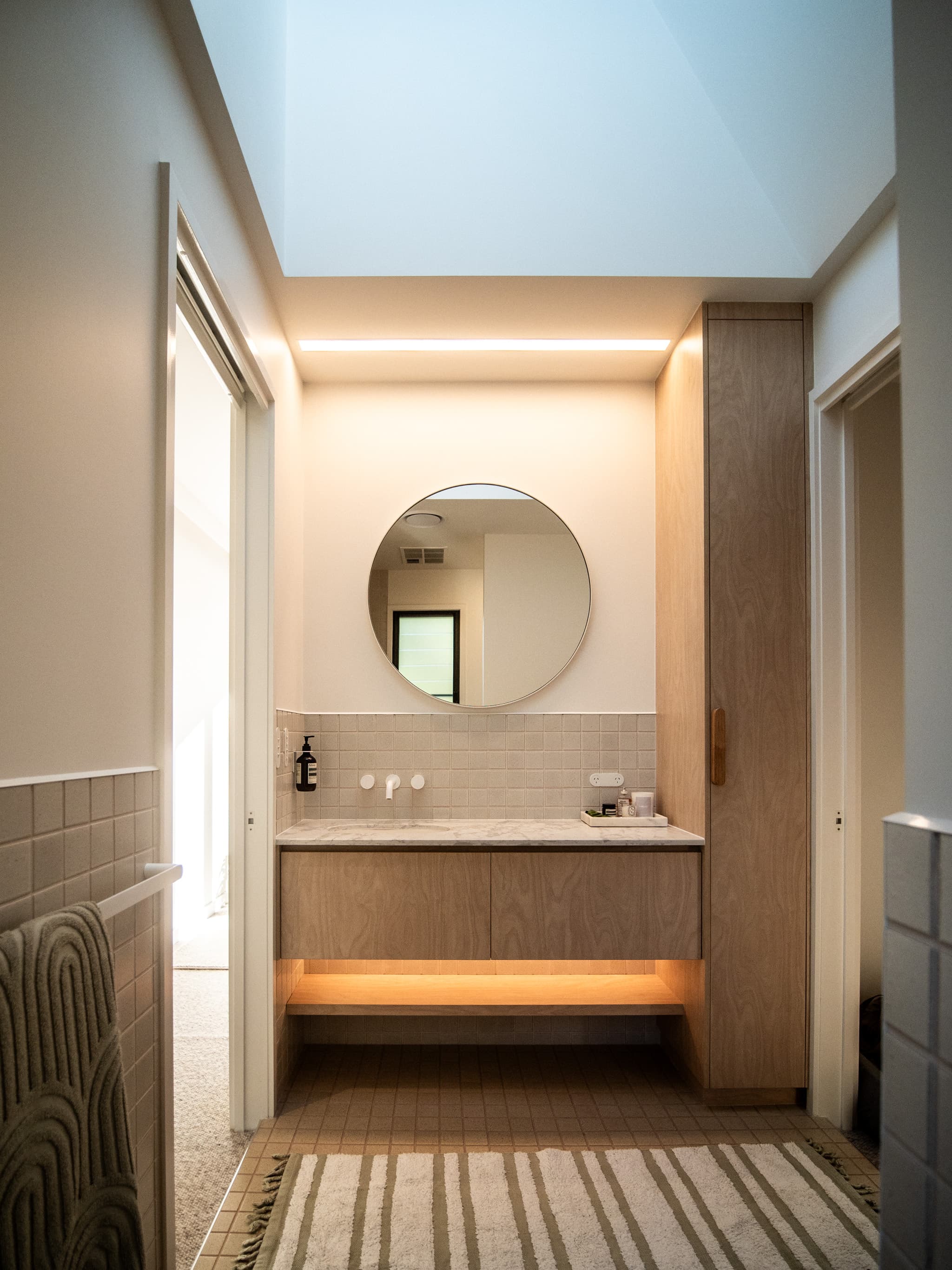 Jacaranda Highside bathroom vanity with a round mirror, marble top and skylight above