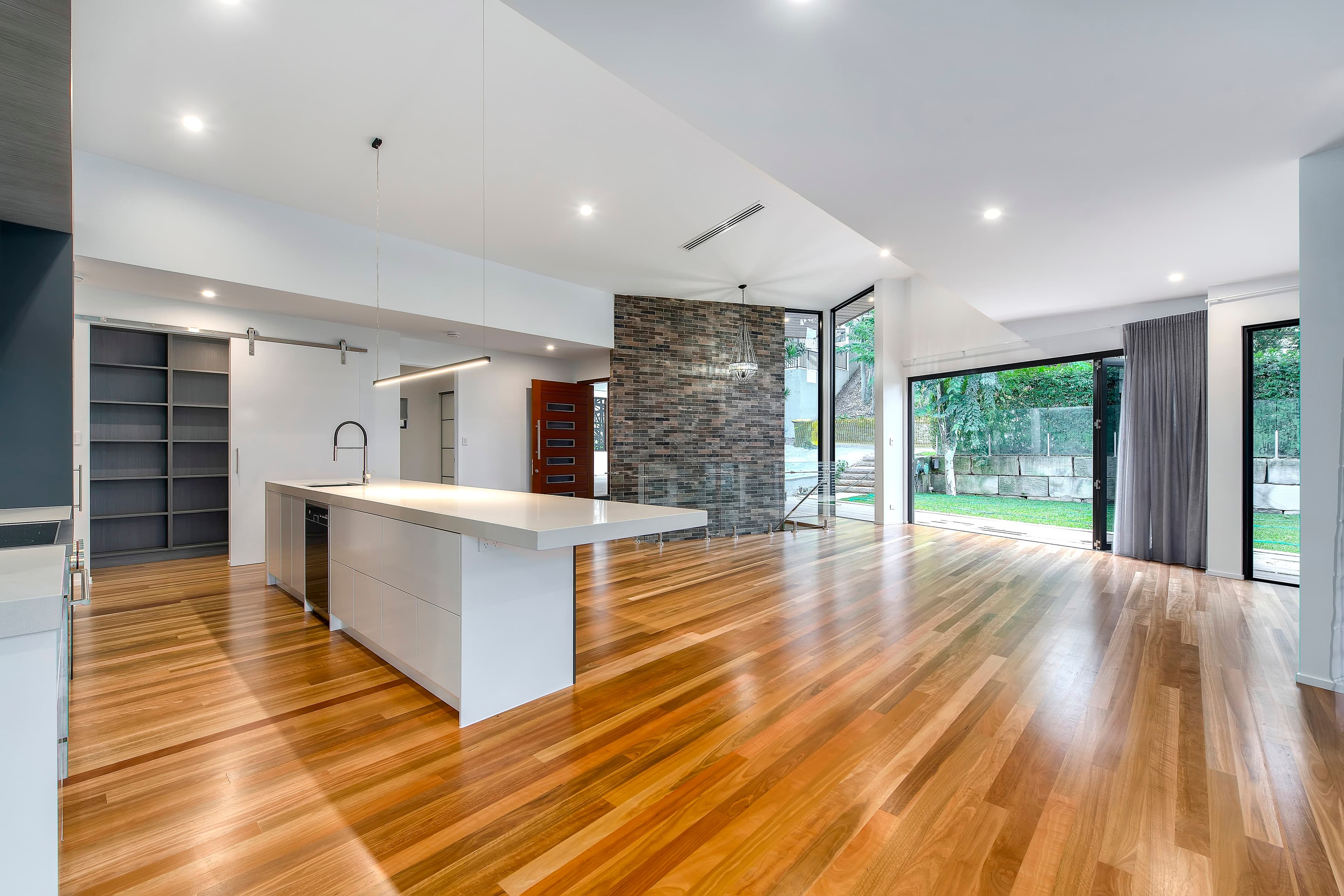 Langside Road kitchen and living opening to the rear lawn past a brick feature wall