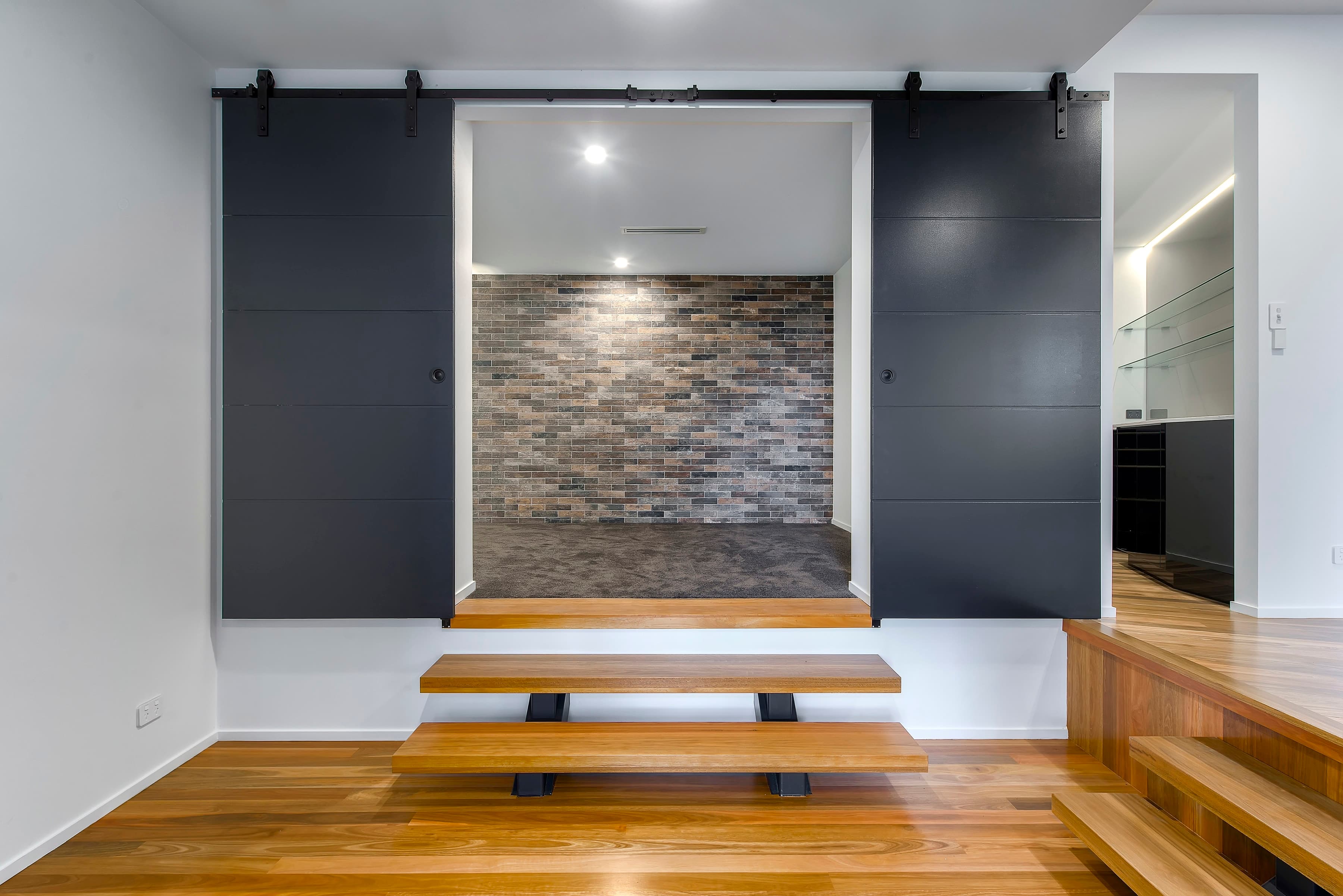Langside Road media nook framed by black sliding doors and timber bench steps