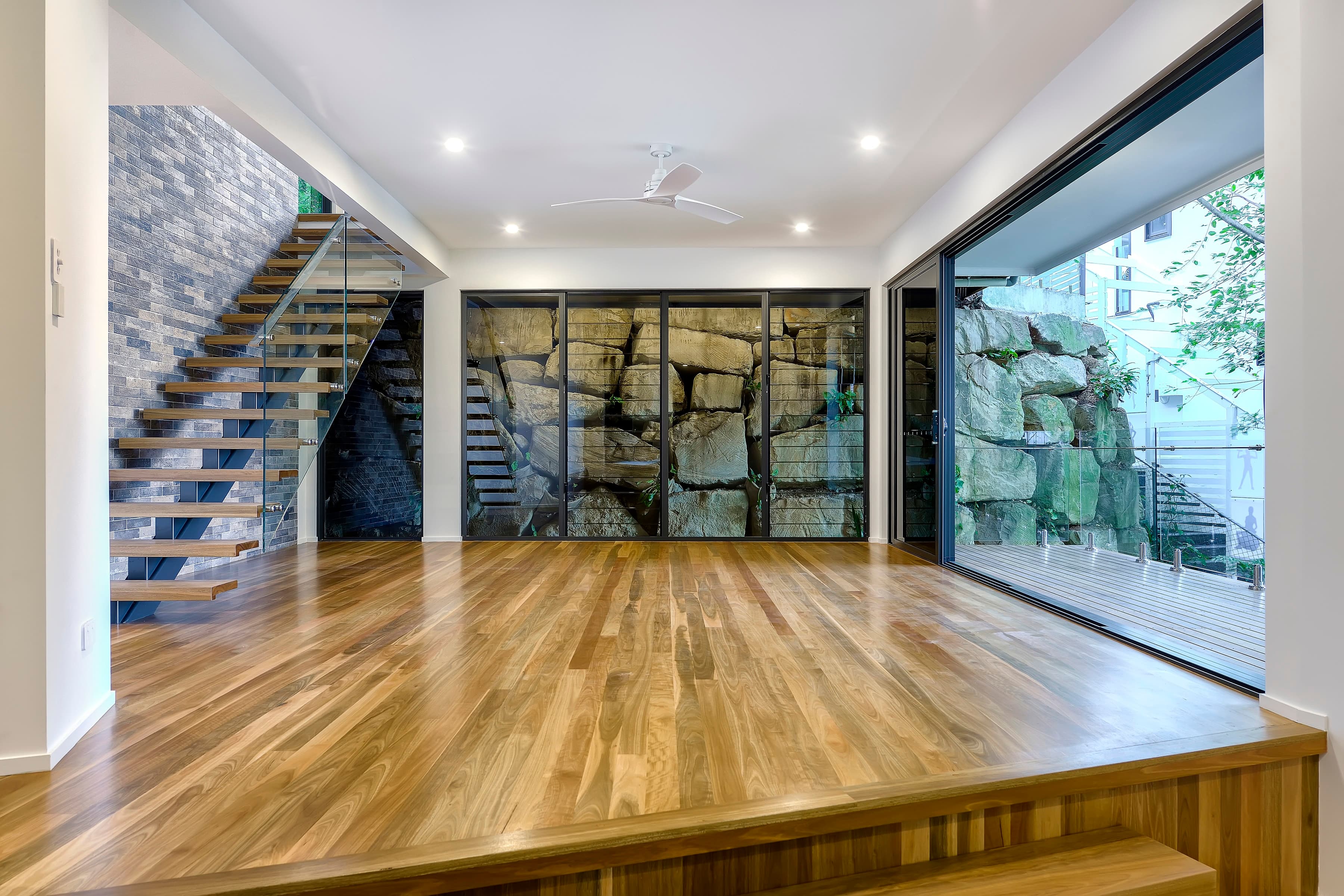 Langside Road lower living opening to the deck against a sandstone boulder wall