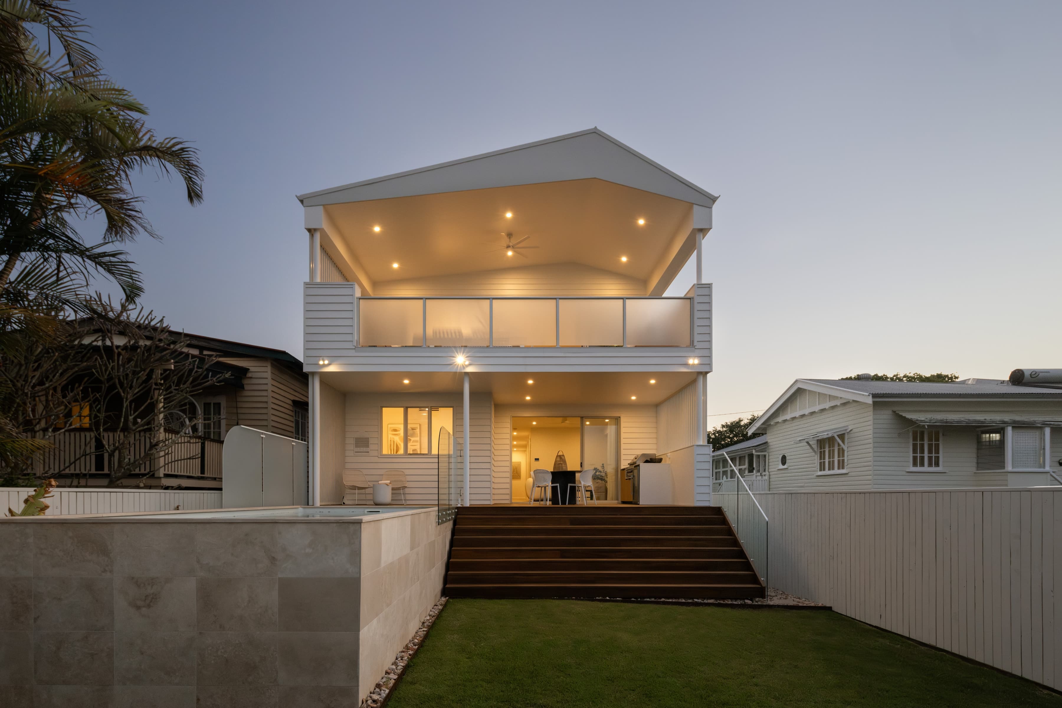 Mesa rear elevation at dusk, lit from within above the raised pool
