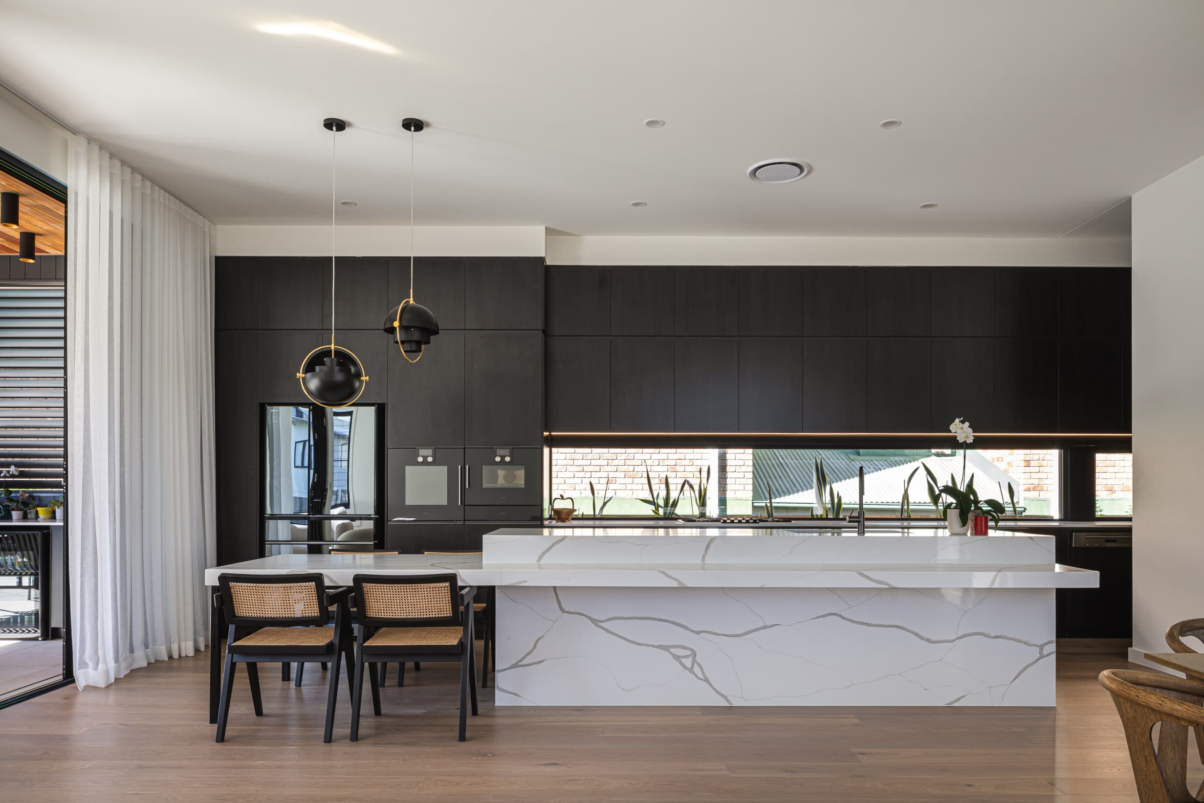 Z House kitchen with black joinery and a marble waterfall island