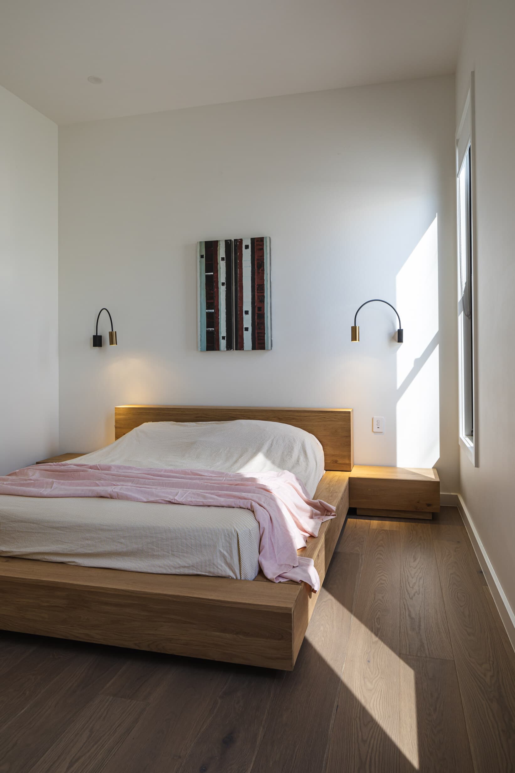 Z House bedroom with a solid timber platform bed and brass wall lights