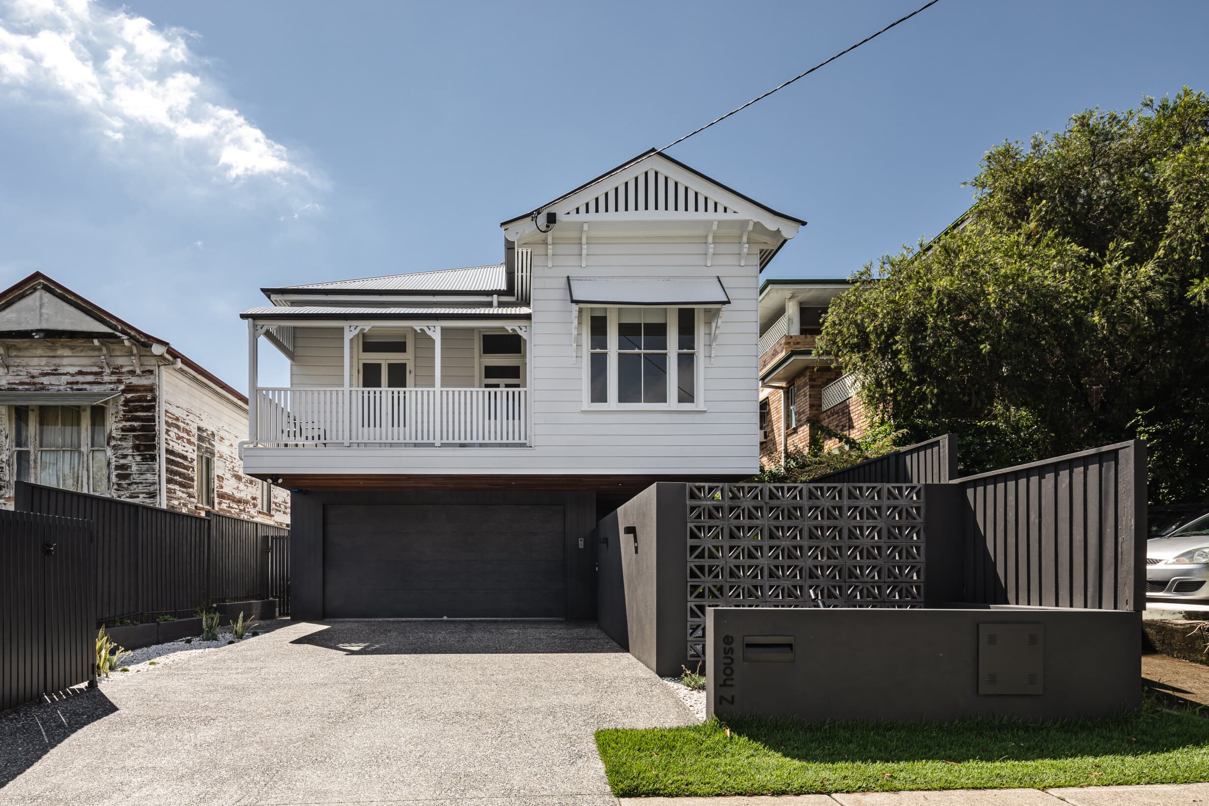 Z House street frontage, the original Queenslander above a dark garage